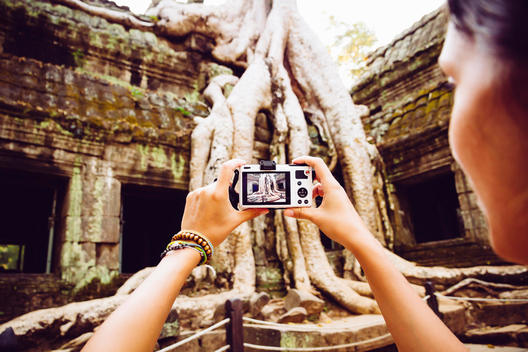 Cambodia, Angkor Wat, Woman takes pictures of the famous tree in Ta Prohm Temple