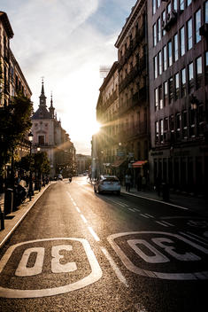 The setting sun shines down a shop lined street near the art district of Madrid, Spain.