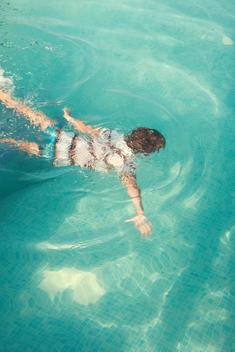 Five Year Old Boy Swimming Underwater In A Pool