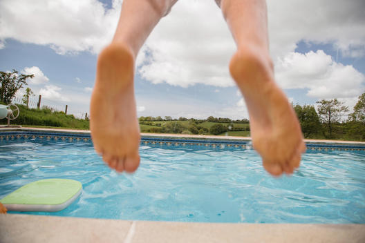 View of a mans feet as he jumps into a swimming pool