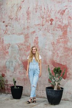 A girl posing in front of a wall.