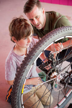Caucasian father teaching son to repair bicycle