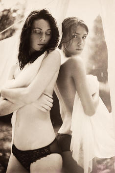 Two topless woman wrapped in sheets hung on clothes lines.
