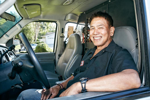 Pacific Islander plumber smiling in van