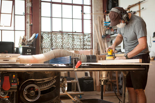 A man using a hand sander in his work shop