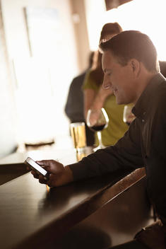 Businessman looking at cellphone in a wine bar