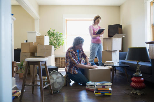 Couple packing moving boxes in living room