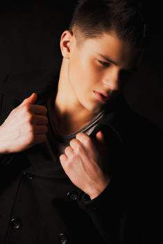 Male model wearing black coat, shooting on black background.