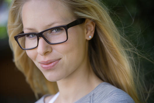 Germany, Bavaria, Schaeftlarn, Young woman wearing thick rimmed spectacles, smiling, portrait, close up