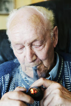 Germany, Senior man holding pipe, close up