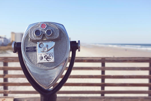 Beach binoculars on a sunny pier near the ocean