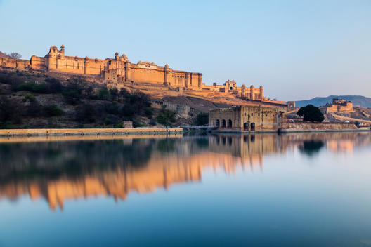Amber Fort reflecting in still river under blue sky, Jaipur, Rajashan, India