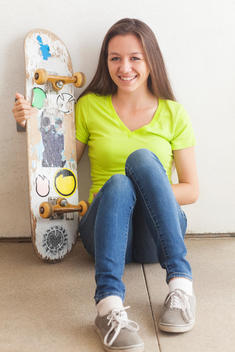 Mixed race teenage girl holding skateboard