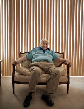 Portrait Of A Senior Man In Front Of Vertical Blinds.