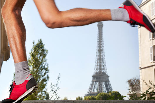 Detail of male legs in athletic shoes, running, Eiffel Tower background