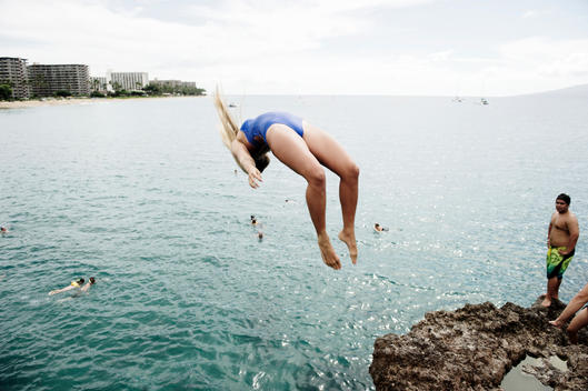 Thrill seeking girl back flips off a cliff in Hawaii.