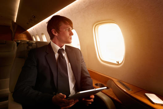 Caucasian businessman using digital tablet on private jet