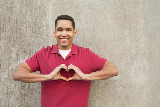 Mixed race man making heart-shape with hands