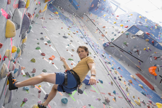 Portrait of man climbing indoor rock wall