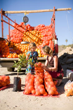 Mother and daughter buying fresh oranges out of the back of a truck while traveling in Mexico