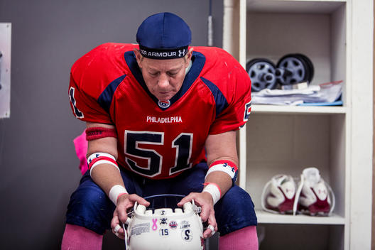 A women\'s football player sits dejected in the locker room during halftime.