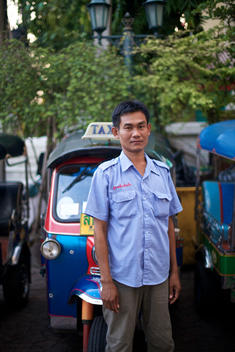 Tuk Tuk driver standing in front of his Tuk Tuk in Bangkok, Thailand