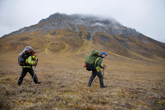 Backpackers hike beneath a limestone monolith along Accomplishment Creek in Alaska\'s Arctic National Wildlife Refuge.