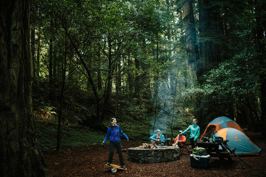 A bunch of twenty-something\'s camping and hanging out by the fire pit in the forest.