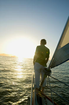 Man on sailboat looking at sunrise