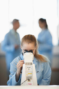 Caucasian student using microscope in lab