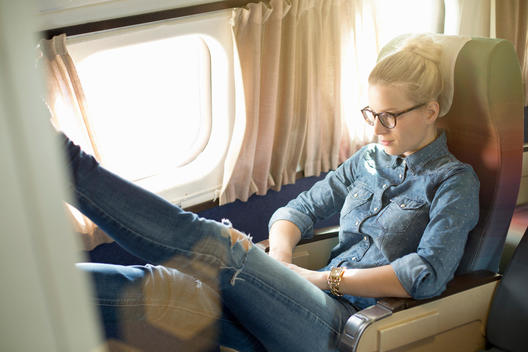 Portrait of young woman sitting on train with feet up