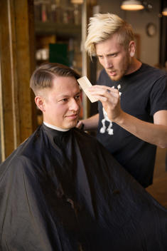 A man get?s a haircut at a barbershop.