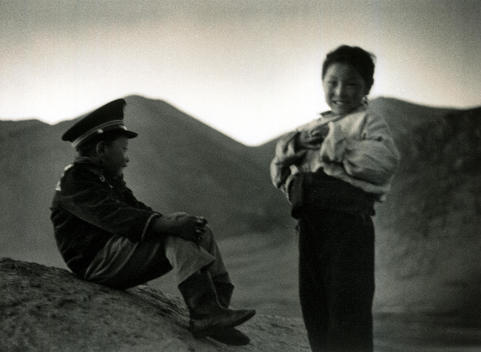 Young Boy In Chinese Army Uniform With Young Girl At Dusk In Tibetan Mountains