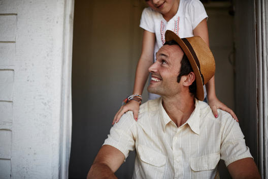 Man in hat sitting in door with girl hugging shoulders