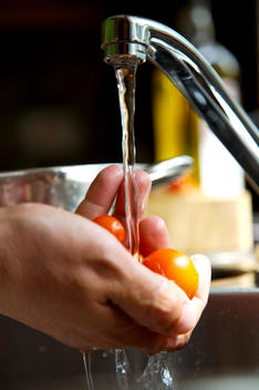 Man's hands washing cherry tomatoes with running water