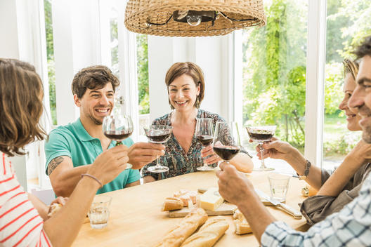 Five adult friends making a toast at dining table