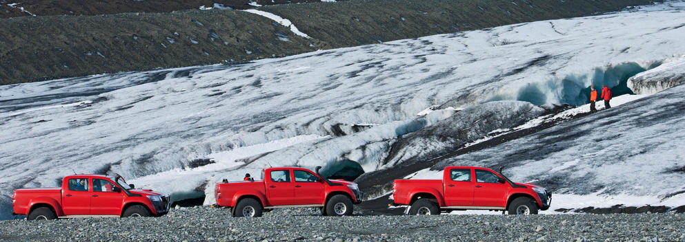 Panoramic view of hikers exploring cave and a row of off road vehicles, Breidamerkurjokull, East Iceland, Iceland