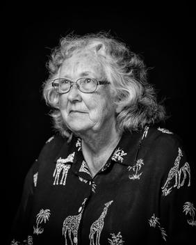 Black and white portrait of elderly woman wearing glasses giraffe shirt looking away