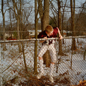 High School Football Player Climbing Over Fence