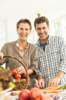 Portrait of couple preparing fresh vegetables in kitchen