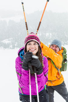Young couple being silly while taking a break from their snowshoe adventure