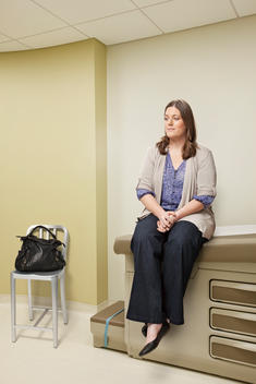 Female patient sitting on examination table in medical office exam room.