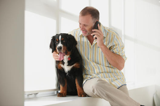 Caucasian man hugging dog and talking on cell phone