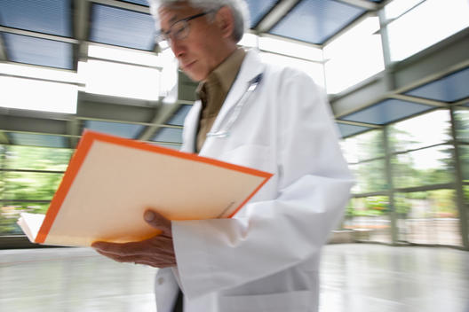Asian doctor walking and looking at medical record