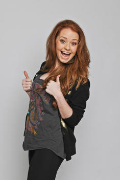 Red-haired female in her 20s looking happy with both her thumbs up