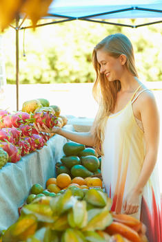 Caucasian woman holding dragon fruit at produce stand