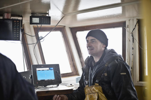 Rob Lamont. Fisherman and Skipper of the Vital Spark oyster fishing boat standing next to the GPS tracking equipment that keeps track of where they have fished and where the oyster farms are on the bed of the loch.
