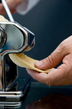 Close up of a hand holding pasta dough coming out of a pasta maker
