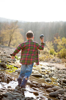 boy throwing rock in creek