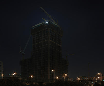 Massive high-rise with cranes under construction in Seoul at night.